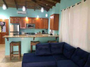 a living room with a blue couch and a kitchen at Casita Azul in Bastimentos