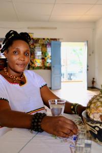 a woman sitting at a table with a plate of food at Chambres d'hôtes - Chez Papa Sêdjro in Porto-Novo +9 photos