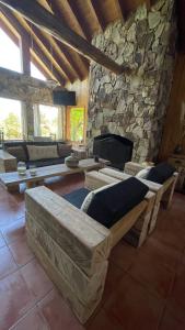 sala de estar con chimenea de piedra y sofá en Hostería Brisas del Cerro en Villa La Angostura