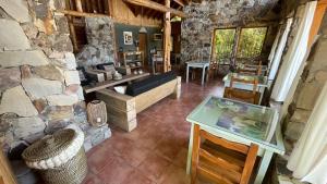 a living room with a stone wall and a table at Hostería Brisas del Cerro in Villa La Angostura