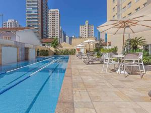 a swimming pool with chairs and a table and an umbrella at Vila Olimpia Hotel in Sao Paulo