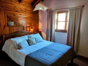 1 dormitorio con cama con sábanas azules y ventana en Cabaña Camalen en San Martín de los Andes