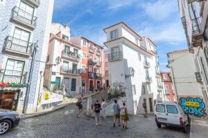 un grupo de personas caminando por una calle con edificios en Typical Alfama Apartment, by TimeCooler en Lisboa