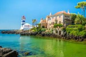 a house and a lighthouse in the ocean with green water at Enjoy Beloura! in Sintra