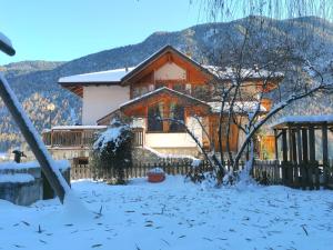una casa cubierta de nieve con una montaña en el fondo en Casa BlueSky - Val di Sole in Trentino, en Croviana