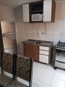 Il comprend une petite cuisine équipée d'un évier et d'une cuisinière. dans l'établissement Apartamentos na Quadra do Mar, à Guaratuba