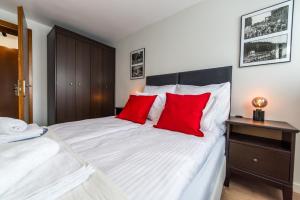 - une chambre avec un grand lit blanc et des oreillers rouges dans l'établissement Apartament Wilaneska, à Krynica-Zdrój