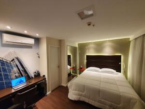 a bedroom with a bed and a desk with a laptop at Vila Olimpia Hotel in Sao Paulo