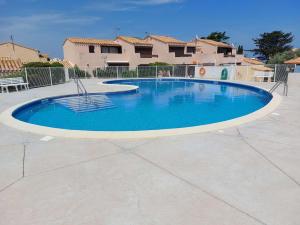 a large blue swimming pool in a courtyard at Studio Résidence Aphrodite Village naturiste en bord de mer à Leucate in Leucate