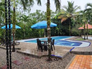 a table with a blue umbrella next to a swimming pool at Casa Montenegro in Villavicencio