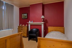 1 dormitorio con 1 cama, 1 silla y paredes rojas en Vakantiehuisje Amaryllis, en Brujas