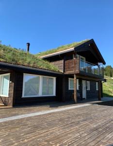 a house with a grass roof and a wooden deck at Fjelltun Lodge in Sogndal