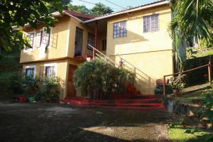 a house with stairs in front of it at La Familia Guest House and Natural Farm in Port Antonio