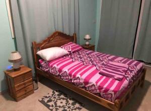 um quarto com uma cama com lençóis rosa e roxo em Sunset View em Bastimentos
