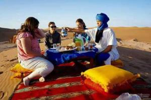 a group of people sitting around a table in the desert at Mhamid Tours in Mhamid