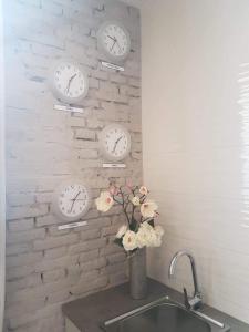 four clocks on a brick wall with a sink at Bonito Alojamiento bien comunicado in Valencia