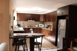 a kitchen with wooden cabinets and a table and a refrigerator at Cozy and Spacious Home with Incredible Location in Cuenca