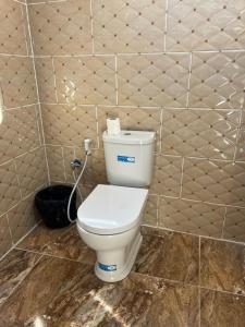 Łazienka z białą toaletą w wyłożonej kafelkami ścianie w obiekcie Wadi Rum Magic Nature Camp w mieście Wadi Rum