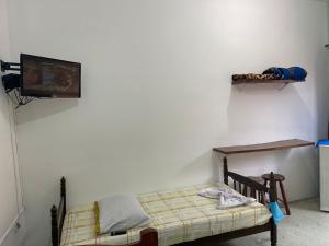 a bedroom with a bed and a tv on a wall at Pousada Nova Opção in Bertioga