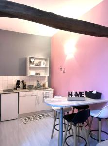 cocina con paredes rosas, mesa y sillas en Chablis: grand studio en plein centre ville en Chablis