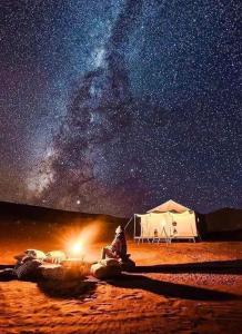a man sitting in front of a tent under the stars at Mhamid Tours in Mhamid
