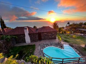 a villa with a swimming pool in front of a sunset at Villa Awara by Rural La Palma in El Pinillo