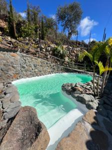 a swimming pool with blue water and rocks at Villa Awara - Piscina privada - Private pool - by Rural La Palma in El Pinillo