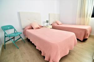 Zimmer mit 2 Betten mit rosa Bettwäsche und einem Stuhl in der Unterkunft Apartamento Martina in Puerto del Carmen