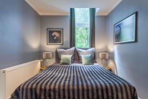a bedroom with a bed with a striped blanket and a window at The Paul II - stylish & central 3 BR apartment, group & family friendly, 4- 6 Guests in Berlin