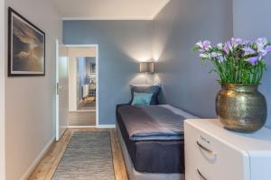 a small bedroom with a vase of flowers on a dresser at The Paul II - stylish & central 3 BR apartment, group & family friendly, 4- 6 Guests in Berlin +12 photos
