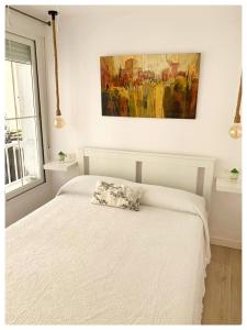 格拉納達的住宿－Apartamento MARIANA，卧室配有白色的床和墙上的绘画作品