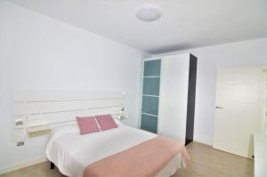 a white bedroom with a bed and a cabinet at Apartamento Martina in Puerto del Carmen