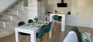 The Green Loft - Wifi, Parking Privado في Camarma de Esteruelas: غرفة معيشة مع طاولة بيضاء وكراسي خضراء