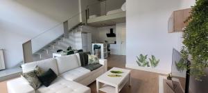 The Green Loft - Wifi, Parking Privado في Camarma de Esteruelas: غرفة معيشة مع أريكة بيضاء ودرج