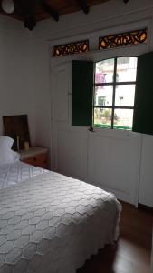 a bedroom with a white bed and a window at Hostal La Cestería Pueblito Boyacense in Duitama