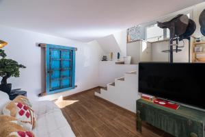 a living room with a flat screen tv and stairs at Casa Estábulo- Cozy Rustic Farmhouse (HORSE LOFT) in Estômbar