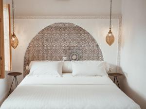 1 dormitorio con 1 cama blanca grande y cabecero ornamentado en Riad Le Petit Joyau en Marrakech