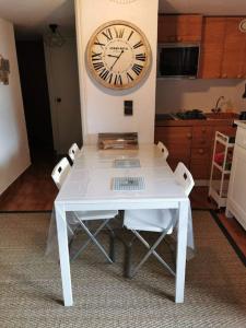 una mesa blanca en una cocina con un reloj en la pared en Duplex cocooning avec vue lac et montagnes en Savines
