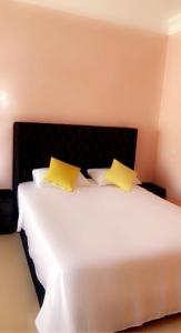 een slaapkamer met een wit bed en 2 gele kussens bij Superbe appartement à la Palmeraie in Marrakesh