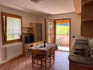 eine Küche mit einem Tisch und einer Flasche Wein darauf in der Unterkunft Appartamenti Rì de Clama in Andalo