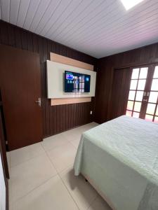 Schlafzimmer mit einem Bett und einem Flachbild-TV in der Unterkunft Casa Aconchegante com Privacidade em Balneário Rincão in Aliatar