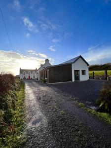 a house on the side of a gravel road at Wild Wild West Holiday Cottages in Castletownbere