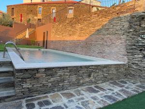a swimming pool in a stone wall with a stone at Castas do Douro in Tabuaço