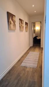 Luxury 1 bedroom flat in the heart of Wood Green في لندن: ممر مع غرفة معيشة مع لوحات على الحائط