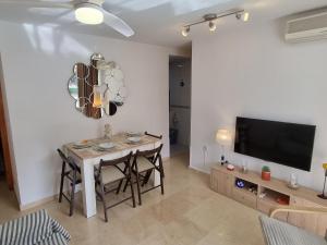 a living room with a table and a tv at Ideal familias en urbanización de lujo a 600m de la playa Levante con Wifi, AC y Parking in Benidorm