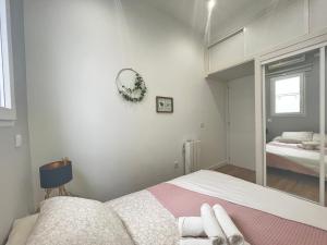 Habitación blanca con cama y espejo en Piso Lacy Ile, en Madrid