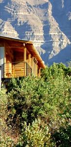 une cabane en rondins avec une montagne enneigée en arrière-plan dans l'établissement Cordillera Flora endógena Bosque Esclerófilo, à San José de Maipo