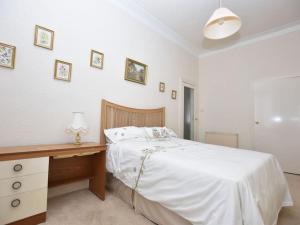 a white bedroom with a bed and a desk at Lovely flat overlooking the Clyde in Gourock