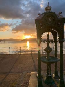 a clock on the beach with the sunset in the background at Lovely flat overlooking the Clyde in Gourock