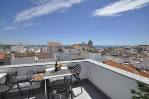 a balcony with a table and chairs on a roof at Torrinha House in Lagos
